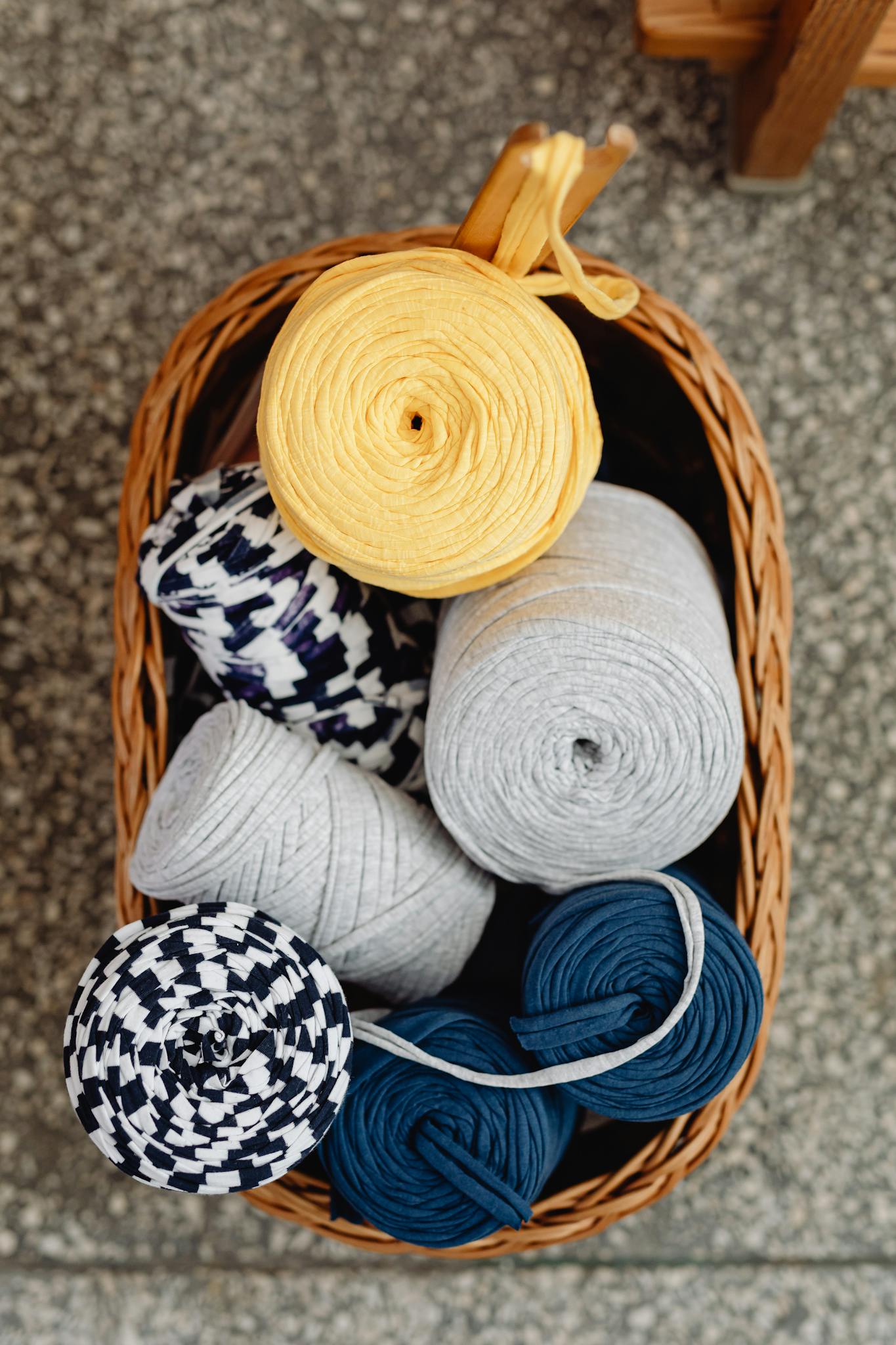 A top-down view of vibrant yarn spools neatly arranged in a wicker basket.